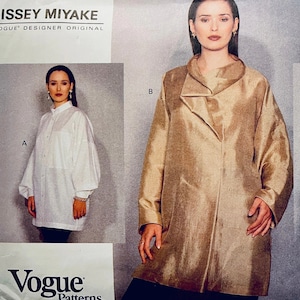 May include: Vogue Patterns Issey Miyake designer original sewing pattern. The pattern features two women's garments: a white blouse with voluminous sleeves and a gold-colored coat with a unique collar design. The Vogue Patterns logo is visible.