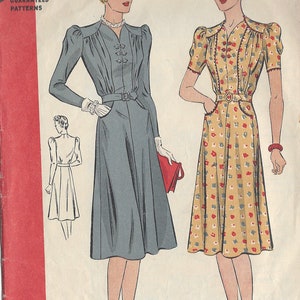 Può includere: Modello di cucito vintage degli anni '40 per un abito con un corpetto aderente e una gonna ampia. Il modello è per un busto di taglia 40 e un'anca di 43. Il modello è illustrato con due donne che indossano l'abito, una in tinta unita blu e l'altra con una stampa floreale.