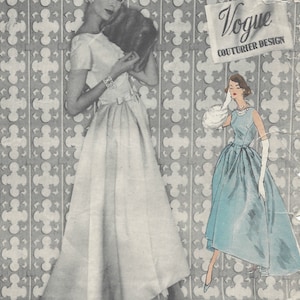 May include: A vintage Vogue Couturier Design pattern for a dress. The pattern is for a white dress with a full skirt and a fitted bodice. The pattern is number 990.