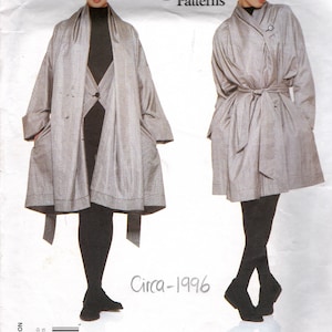 Könnte beinhalten: Vogue Patterns Schnittmuster für einen grauen Mantel mit Bindegürtel. Das Schnittmuster ist von Issey Miyake und stammt aus dem Jahr 1996.