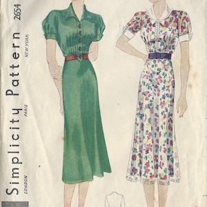 Op de afbeelding: Vintage Simplicity naaipatroon voor een jurk, met twee modellen die verschillende jurkstijlen dragen. Het patroonnummer is 2654 en de maat is 14. De jurk links is groen en de jurk rechts is bloemig.