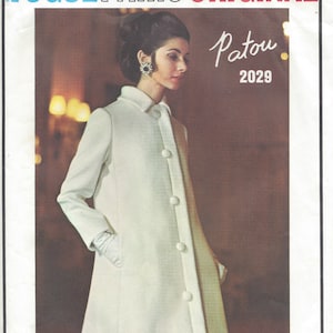 Könnte beinhalten: Vogue Paris Original Schnittmuster für einen weißen Mantel mit Kragen und Knöpfen. Das Schnittmuster ist von Patou und die Nummer ist 2029.