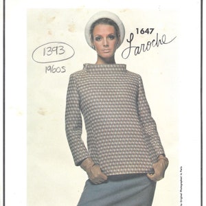 May include: A vintage sewing pattern featuring a woman wearing a brown and white checked top with a high neck and long sleeves, a blue skirt, and a white hat. The pattern is labelled "Vogue Paris Original 1647 Laroche 1393 1960s".