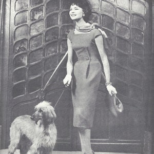 May include: A black and white photograph of a woman wearing a grey dress and heels, walking a white Afghan hound. The woman is holding a handbag and a lead. The photo is from a Vogue Paris Original pattern, designed by "Denis 1680".