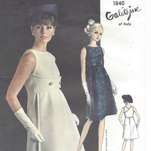 May include: Vogue Couturier Design pattern 1840 Galitzine of Italy, featuring two women wearing dresses. One woman is wearing a white dress with a button detail and the other is wearing a blue dress with a button detail. Both women are wearing white gloves.