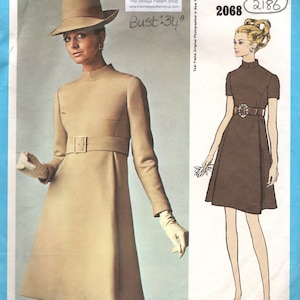 May include: A vintage sewing pattern for a dress with a high neck and a belt. The pattern is from the 1960s and is called "Vogue Americana." The pattern number is 2068 and 2186. The bust measurement is 34 inches.