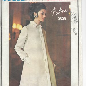 May include: A vintage Vogue Paris Original sewing pattern for a white coat, designed by Patou. The pattern number is 2029 and the year is 1960s.