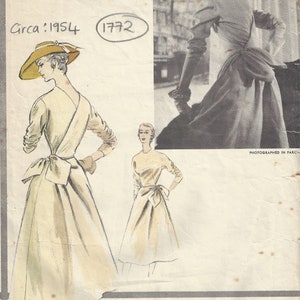 Può includere: Un modello di cucito vintage Vogue del 1954 per un abito con un fiocco in vita. Il numero del modello è 1772. L'abito è mostrato in due pose diverse, una con un cappello e l'altra senza.