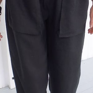 May include: Black trousers with large cargo pockets and a belt. The trousers have a relaxed fit and are made of a soft, comfortable fabric.