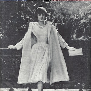 May include: A black and white photo of a woman wearing a white dress and a long coat. She is holding a small clutch purse. The photo is from a Vogue Paris Original magazine from 1957. The text "designed by PATOU" is at the bottom of the photo.