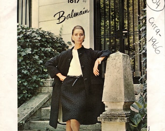 May include: A black and white vintage Vogue Paris Original pattern for a dress by Balmain, design number 1617, circa 1966. The pattern features a model wearing a black dress with a white blouse and a black belt.
