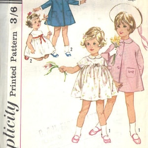 Könnte beinhalten: Vintage Simplicity Schnittmuster für ein Kleinkindkleid mit drei verschiedenen Stilen. Das Muster stammt aus dem Jahr 1964 und enthält Anleitungen für ein blaues Kleid, ein weißes Kleid mit Blumenmuster und einen rosa Mantel. Die Musternummer lautet 5335.
