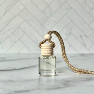 以下が含まれることがあります： 木製のキャップと装飾的なロープが付いた、小さな透明なガラス瓶。 キャップは積み重ねられた木製のリングと小さな木製のビーズでできています。 ロープは金色の斑点のあるベージュ色です。 おそらく芳香剤またはエッセンシャルオイルディフューザーです。