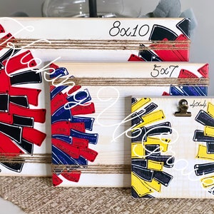 May include: Three wooden picture frames with a cheerleading theme. The frames are decorated with black, red, blue, and yellow pom-poms. The frames are labeled with the sizes 8x10, 5x7, and 4x6.