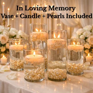 May include: Six clear glass vases with lit floating candles and faux pearls. The vases are filled with water and arranged on a white tablecloth. The background features floral arrangements. Text reads "In Loving Memory Vase + Candle + Pearls Included."