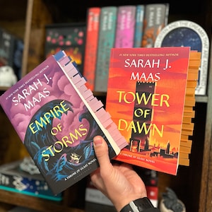 May include: Two paperback fantasy novels by Sarah J. Maas, "Empire of Storms" and "Tower of Dawn", both part of the "A Throne of Glass" series.