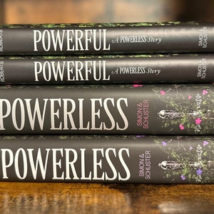 May include: A stack of four black hardcover books with the title "POWERLESS" and the author's name "ROBERTS" on the spine. The books are published by Simon & Schuster.