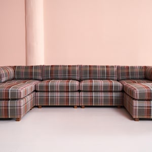 May include: A large sectional sofa with a plaid pattern in shades of brown, gray, and red. The sofa has a chaise lounge on one side and is made up of multiple modular pieces.
