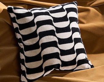 Disponible: Cojín psicodélico de 40x40 cm con diseño de garabatos en negro y gris y cremallera de latón amarillo mostaza.