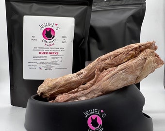 May include: A black bag with the text "Jewel's Ultimate K#Nine" and the words "Pet Treats, Dogs & Cats" on the front. The bag is filled with raw freeze-dried duck necks for dogs. The duck necks are in a black bowl with the same logo as the bag.