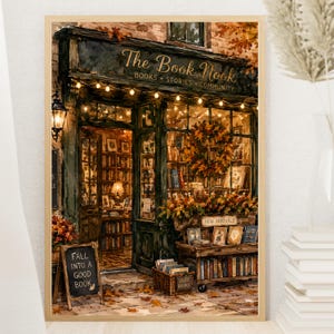 以下が含まれることがあります： The Book Nookというタイトルの書店を描いた額入りアートプリント。温かみのあるストリングライト、秋のリース、本でいっぱいの棚が特徴です。黒板にはFall Into A Good Bookと書かれており、バスケットには古本が入っています。