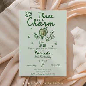 以下が含まれることがあります： 「Three is a Charm」の文字と、妖精の衣装を着た子供の漫画イラストが描かれた、明るい緑色の誕生日招待状。招待状には、パトリックの3歳の誕生日、3月14日午後5時の詳細が記載されています。