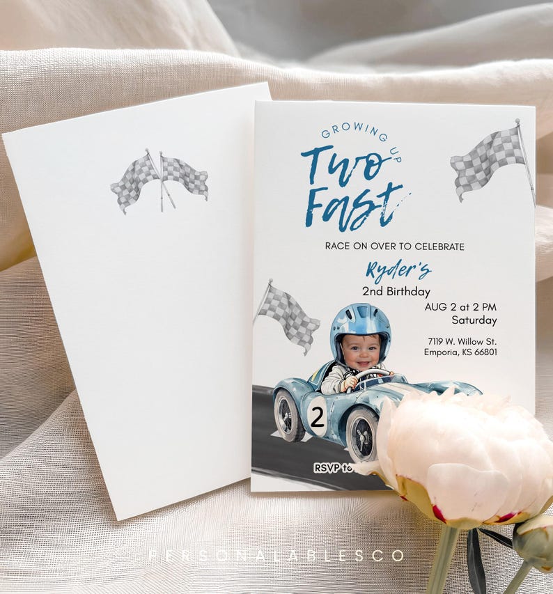 May include: A two-sided invitation with a racing theme. The front features a baby in a blue race car, the text "Growing Up Two Fast", and event details. The back is a blank white card with checkered flags.