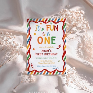 May include: A rectangular birthday invitation card with a scalloped red border and a colorful diagonal striped frame. The text reads: It's FUN to be ONE, Join us to celebrate ADAM'S FIRST BIRTHDAY, SATURDAY, AUGUST 30TH AT 4PM, 68 Court Court Point, Pleasant Beach, NJ 08742, RSVP to Sofia at 910.824.8851.