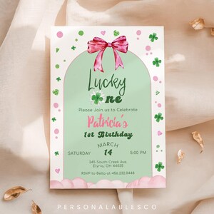 以下が含まれることがあります： 「Lucky One」と「Patricia's 1st Birthday」のテキストが入った、聖パトリックの日のテーマの招待状。ピンクのリボン、クローバー、ハート、明るい緑色の背景が特徴です。招待状には日付、時間、場所が含まれています。