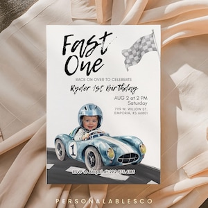 May include: A birthday invitation with the text "Fast One" and "Ryder 1st Birthday". The invitation features a watercolor illustration of a baby in a blue race car. A checkered flag waves in the background.