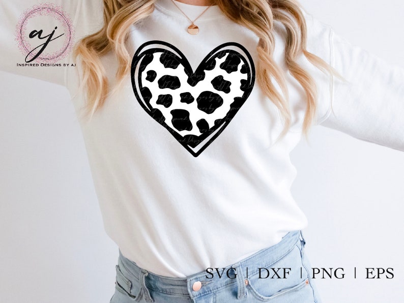 May include: A white t-shirt with a black and white cow print heart design. The text "SVG | DXF | PNG | EPS" is printed at the bottom of the shirt.