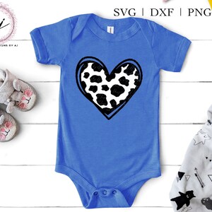 May include: A blue baby onesie with a black and white cow print heart design.