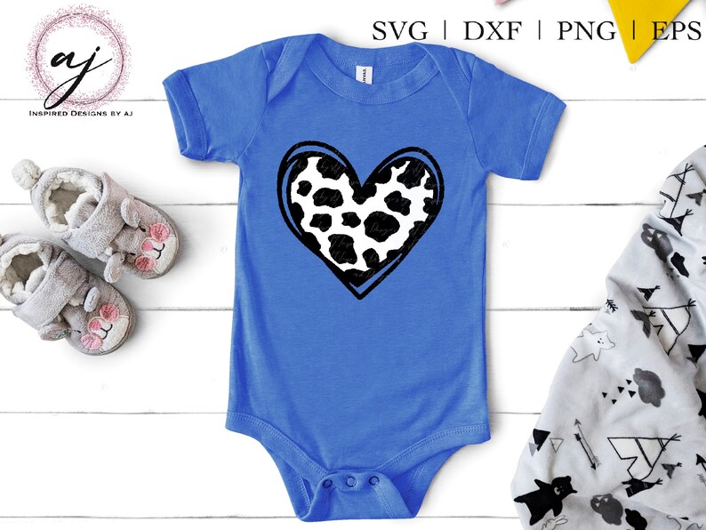 May include: A blue baby onesie with a black and white cow print heart design.