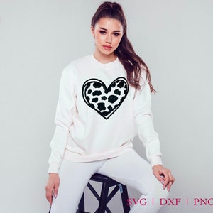 May include: A white sweatshirt with a black outline of a heart filled with a black and white leopard print pattern.
