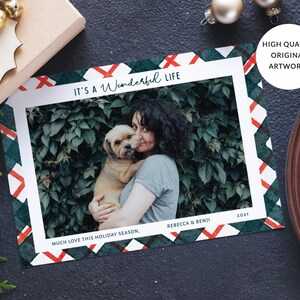 May include: A Christmas card with a green and red plaid pattern. The card features a photo of a woman holding a dog. The text on the card reads "It's a Wonderful Life", "Much Love This Holiday Season", "Rebecca & Benji", and "2021".