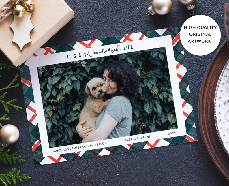 May include: A Christmas card with a green and red plaid pattern. The card features a photo of a woman holding a dog. The text on the card reads "It's a Wonderful Life", "Much Love This Holiday Season", "Rebecca & Benji", and "2021".