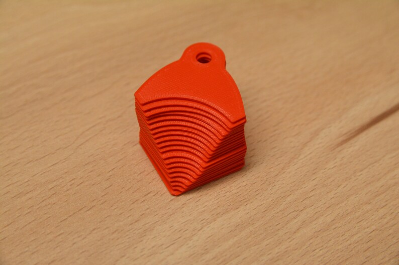 May include: A stack of bright orange plastic keychains shaped like a rounded triangle with a hole at the top.
