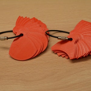 May include: Two sets of orange plastic fan-shaped keychains with black cords and silver clasps.