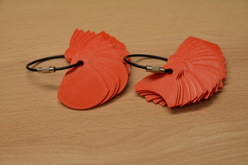 May include: Two sets of orange plastic fan-shaped keychains with black cords and silver clasps.