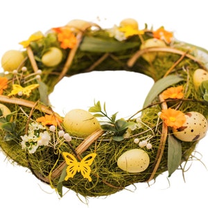K&ouml;nnte beinhalten: Ein gr&uuml;ner Osterkranz, der mit gelben und orangefarbenen Blumen, gesprenkelten und einfarbigen gelben Eiern und gelben Schmetterlingen verziert ist.