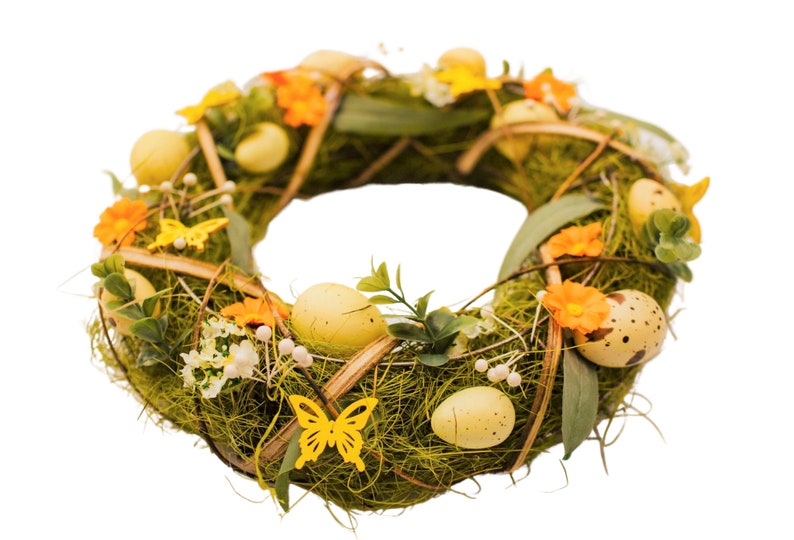 K&ouml;nnte beinhalten: Ein gr&uuml;ner Osterkranz, der mit gelben und orangefarbenen Blumen, gesprenkelten und einfarbigen gelben Eiern und gelben Schmetterlingen verziert ist.