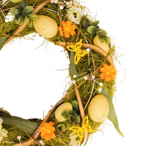 K&ouml;nnte beinhalten: Ein gr&uuml;ner Osterkranz mit gelben Eiern, Schmetterlingen und orangefarbenen Blumen.