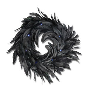 May include: A black feather wreath with blue LED lights. The wreath is made of many black feathers arranged in a circular shape.