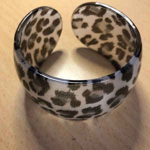 May include: A white and black leopard print plastic bangle bracelet.
