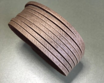 May include: A roll of light brown leather cord, stacked and rolled up. The cord is smooth and has a subtle texture.