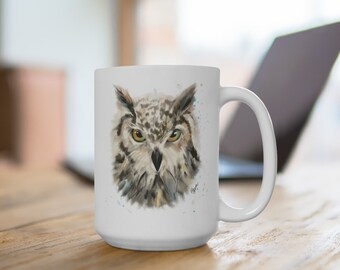 May include: White ceramic mug with a watercolor illustration of an owl's face. The owl has brown and white feathers and yellow eyes. The mug has a black handle.