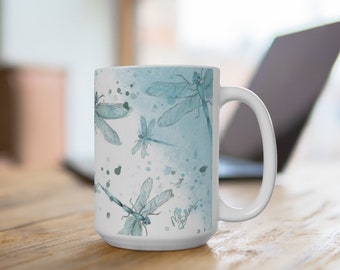 May include: White ceramic mug with a blue watercolor design featuring dragonflies. The mug has a handle and a white background with blue watercolor splatters.