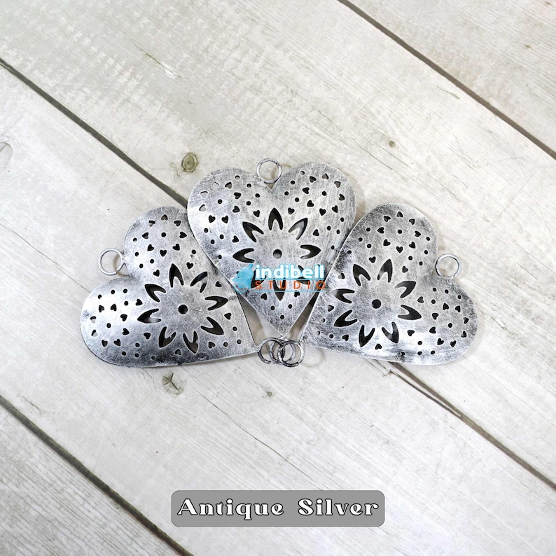3 heart shaped metal cutout with a rustic finish, on the wooden floor.