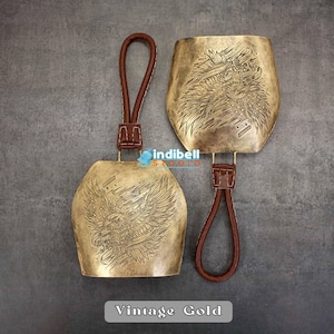 The gold color engraved bell is displayed here, The leather hanger is visible properly here.