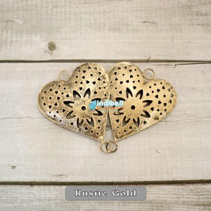Two rustic heart-shaped metal cutouts placed side by side, forming a symmetrical pattern.